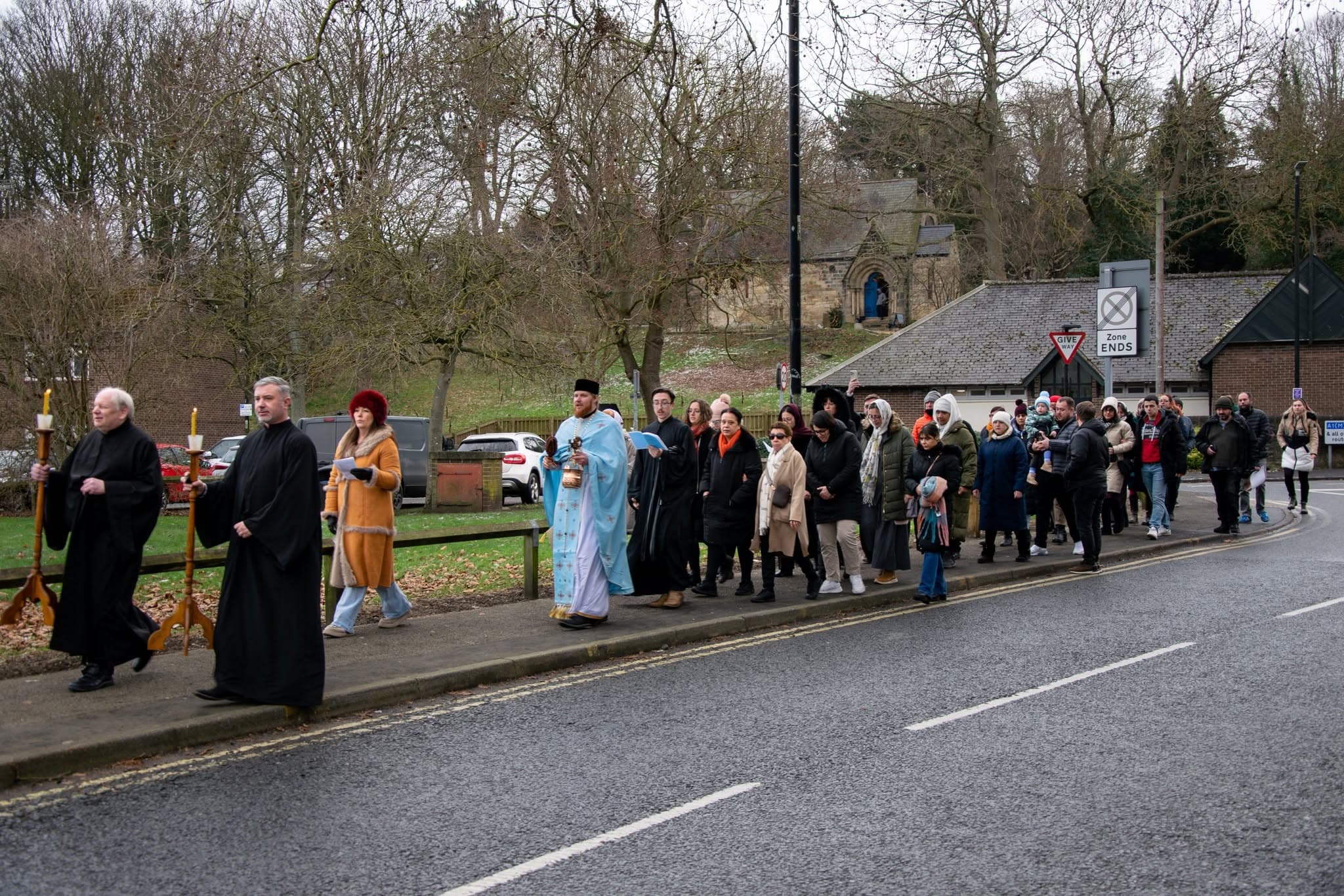 The parish in procession along a Durham roadside - clergy carrying candles and a censer leading, the faithful following in a long line