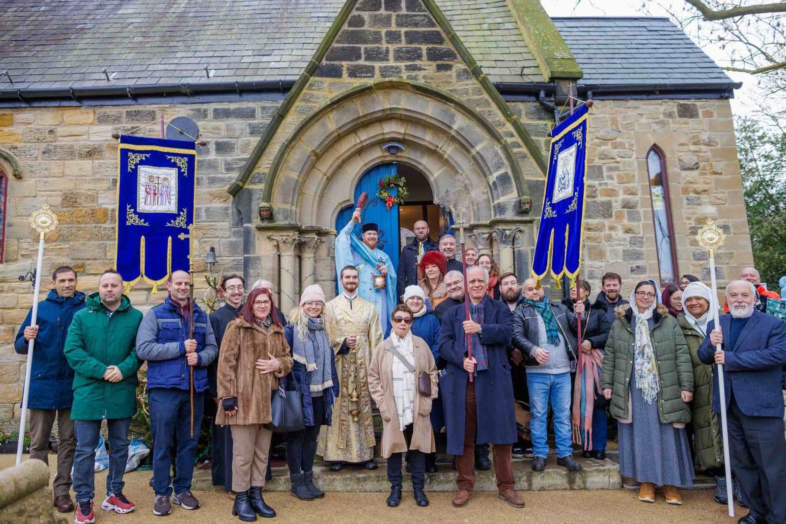 The parish gathered at the church door with banners raised, the clergy at the centre
