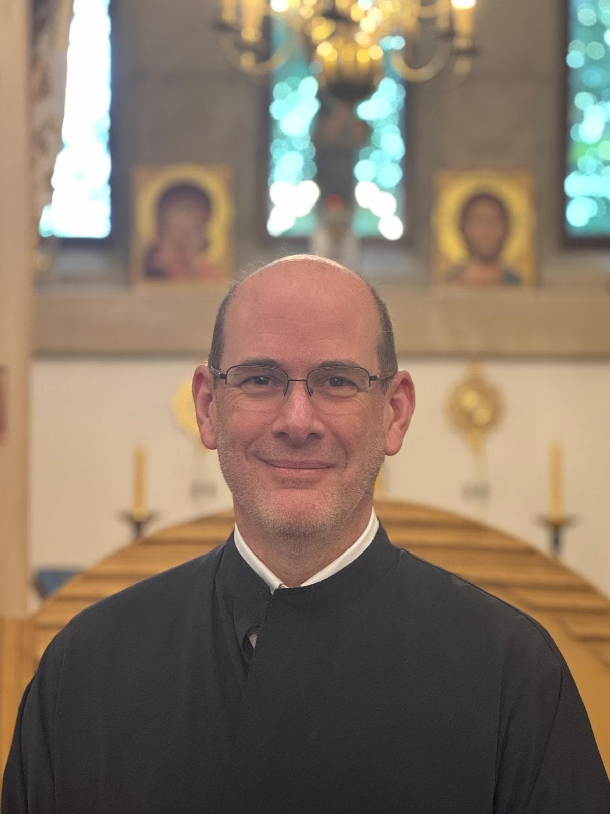 Reader Paul Vickers, in a black cassock, before the iconostasis