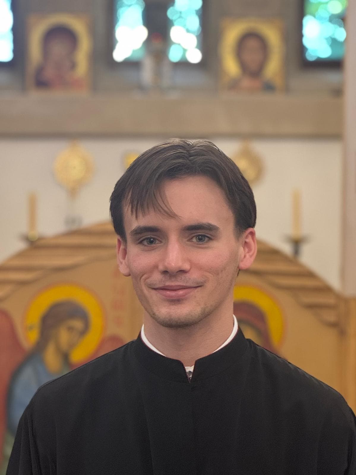 Reader Reece Michael Vasey, in a black cassock, before the iconostasis